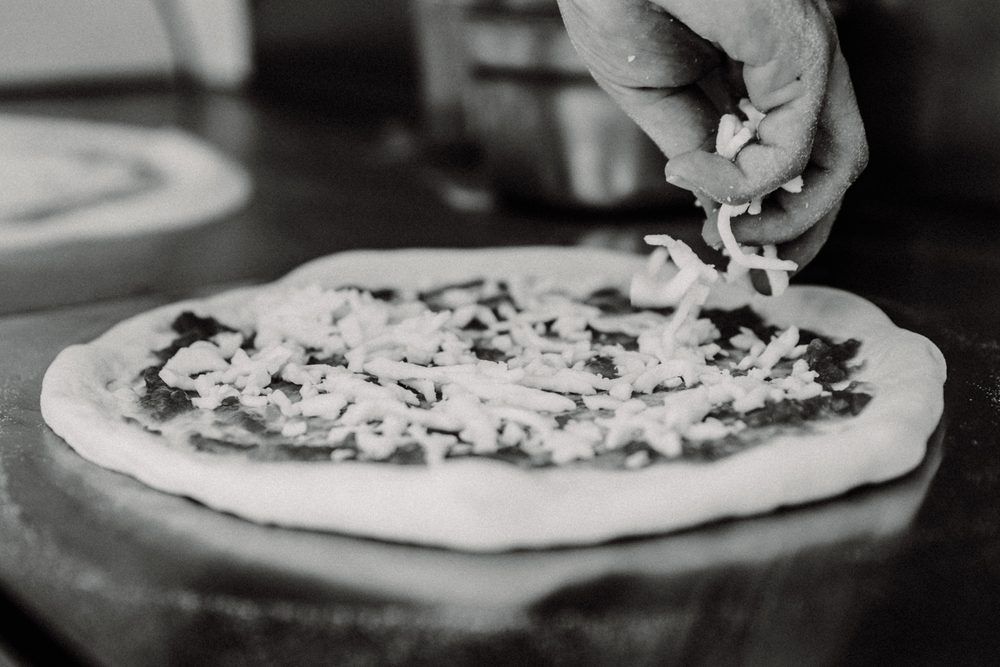 Mozzarella wird auf die Pizza gestreut